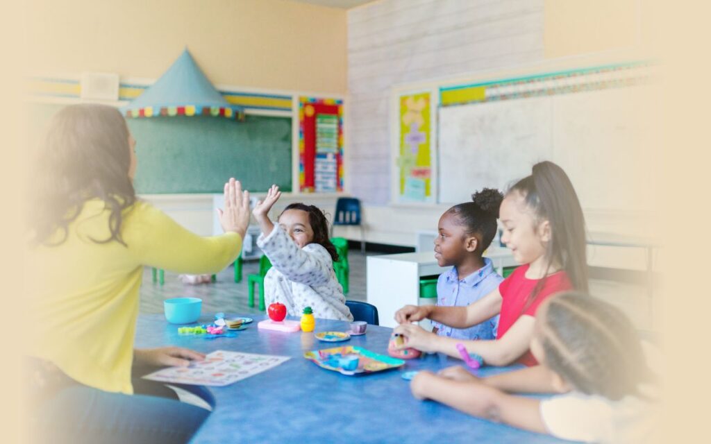 woman giving high five to a child in a classroom setting